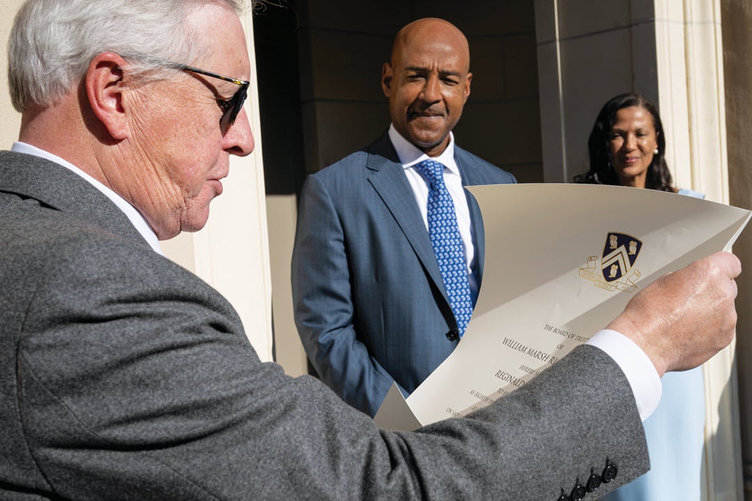 Robert T. Ladd reads the summons to President DesRoches, while Paula Gilmer DesRoches looks on.